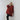 A person with short blonde hair leans against a white wall, wearing an oversized ATHENA NEWTON Pure Cotton Smock Blouse in crimson, paired with black leggings and shoes. With one hand on their head, they gaze confidently into the camera.