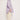 A person stands in profile against a plain background, wearing the versatile ATHENA NEWTON Cotton Smock Blouse in lilac with puffy sleeves and cream-colored pants. Their hair is tied back, and they are wearing light beige sandals with thick soles.